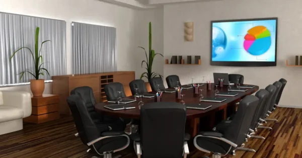 Boardroom table with seats surrounding it and a monitor on the wall with a colorful pie chart.