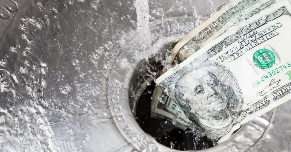 Two $100 bills being washed down a kitchen sink