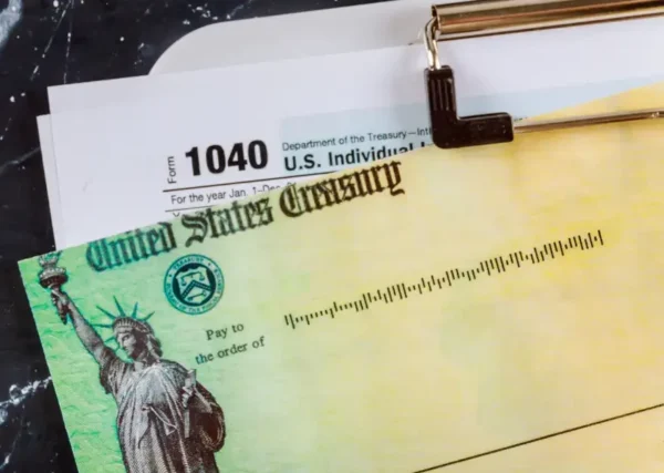 Image shows tax form 1040 as well as a blank United States Treasury check, representing a tax refund.