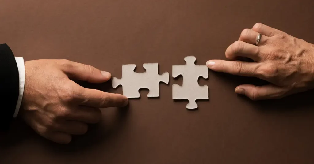 Two people using their hands to put two puzzle pieces together to represent thy buyer and seller.