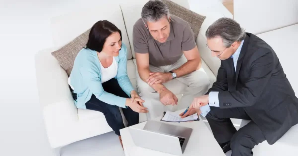 A man in a suit looking at financial documents with a man and a woman to resemble tax planning.