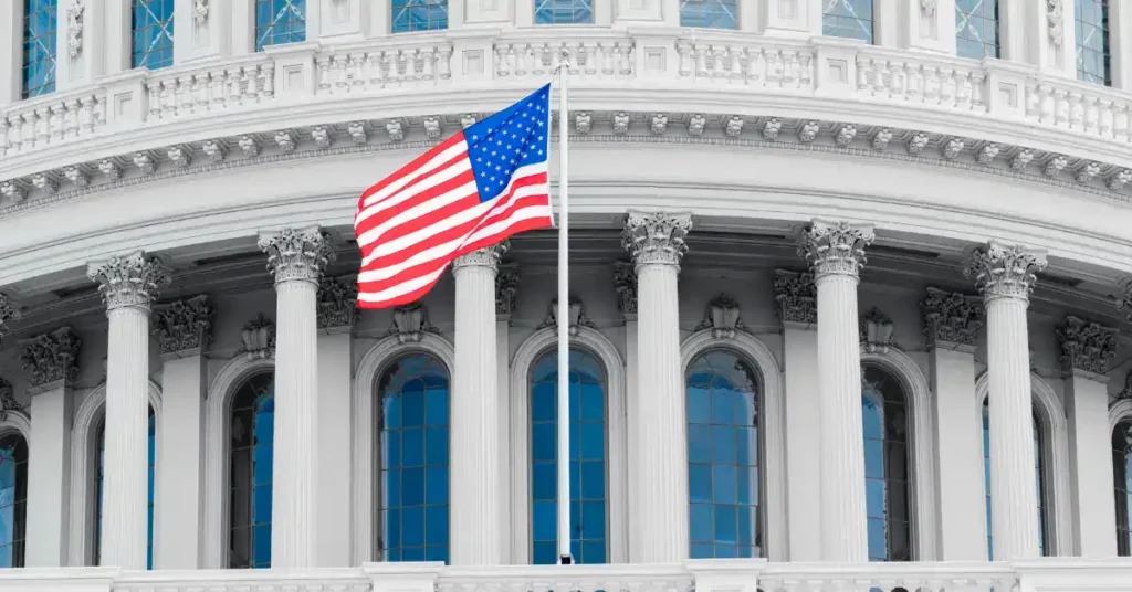 The US Capitol Building, zoomed in, up close of the dome with a US flag in the foreground